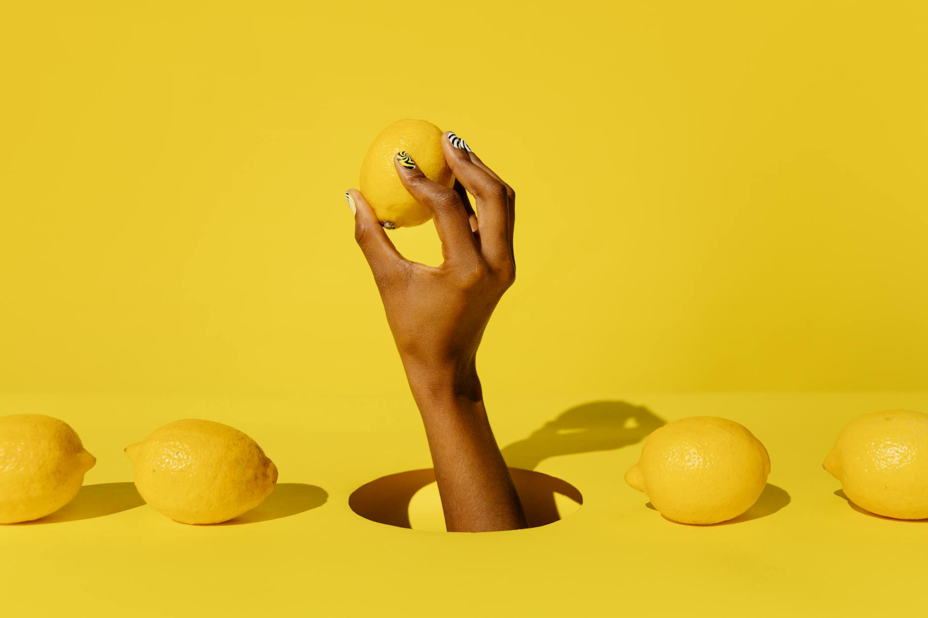 Une main tenant un citron frais sur un fond jaune lumineux, symbole de renouveau et de sensibilité retrouvée