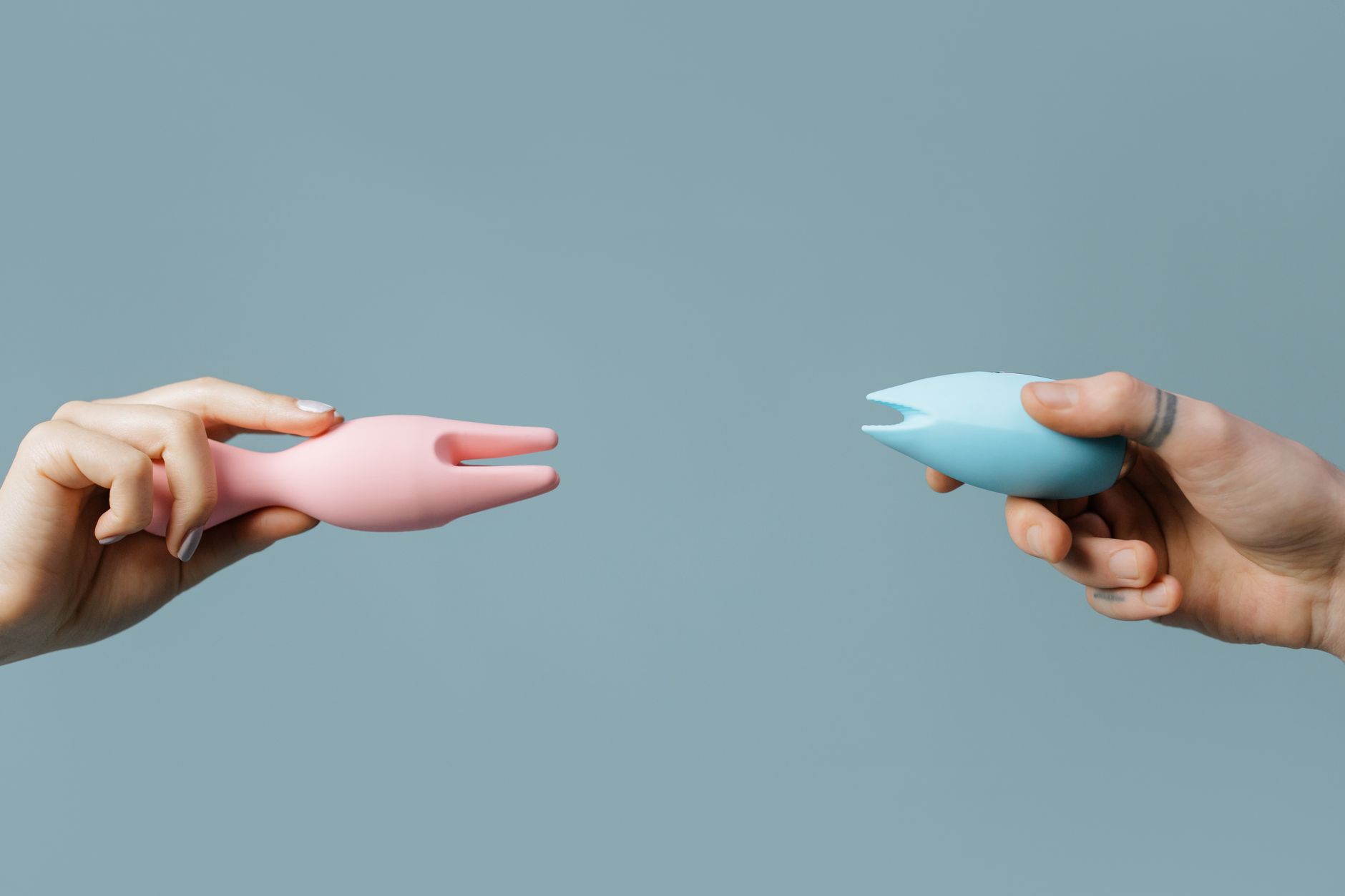 Diverses mains tenant des vibromasseurs colorés sur fond pastel