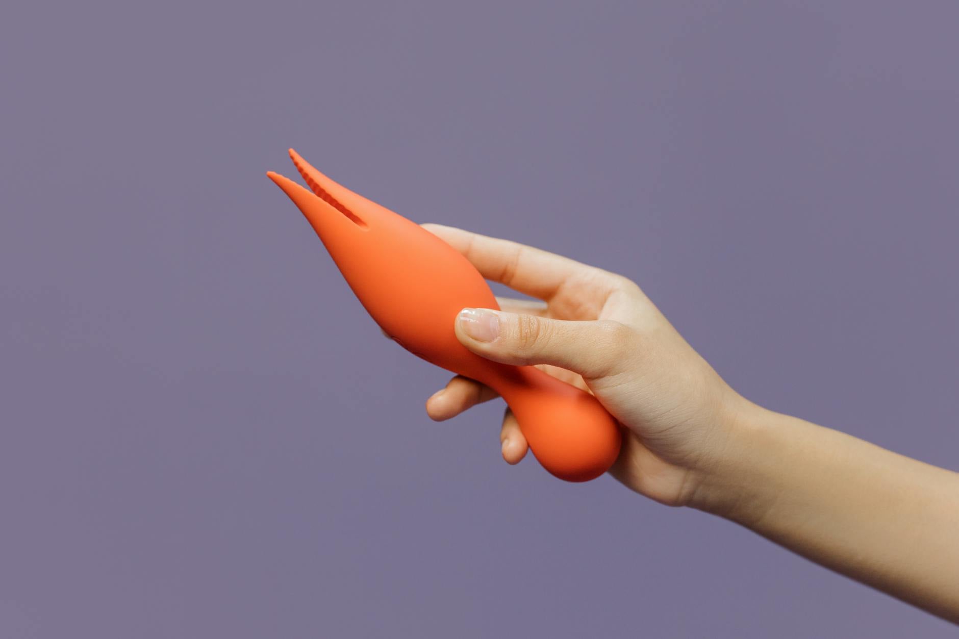 Gros plan d'une main tenant un vibromasseur citron contre un fond violet minimaliste, montrant la sensualité moderne.
