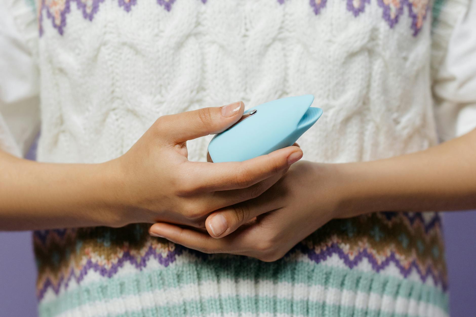 Close-up of hands holding a personal massager, emphasizing intimate connection and shared exploration