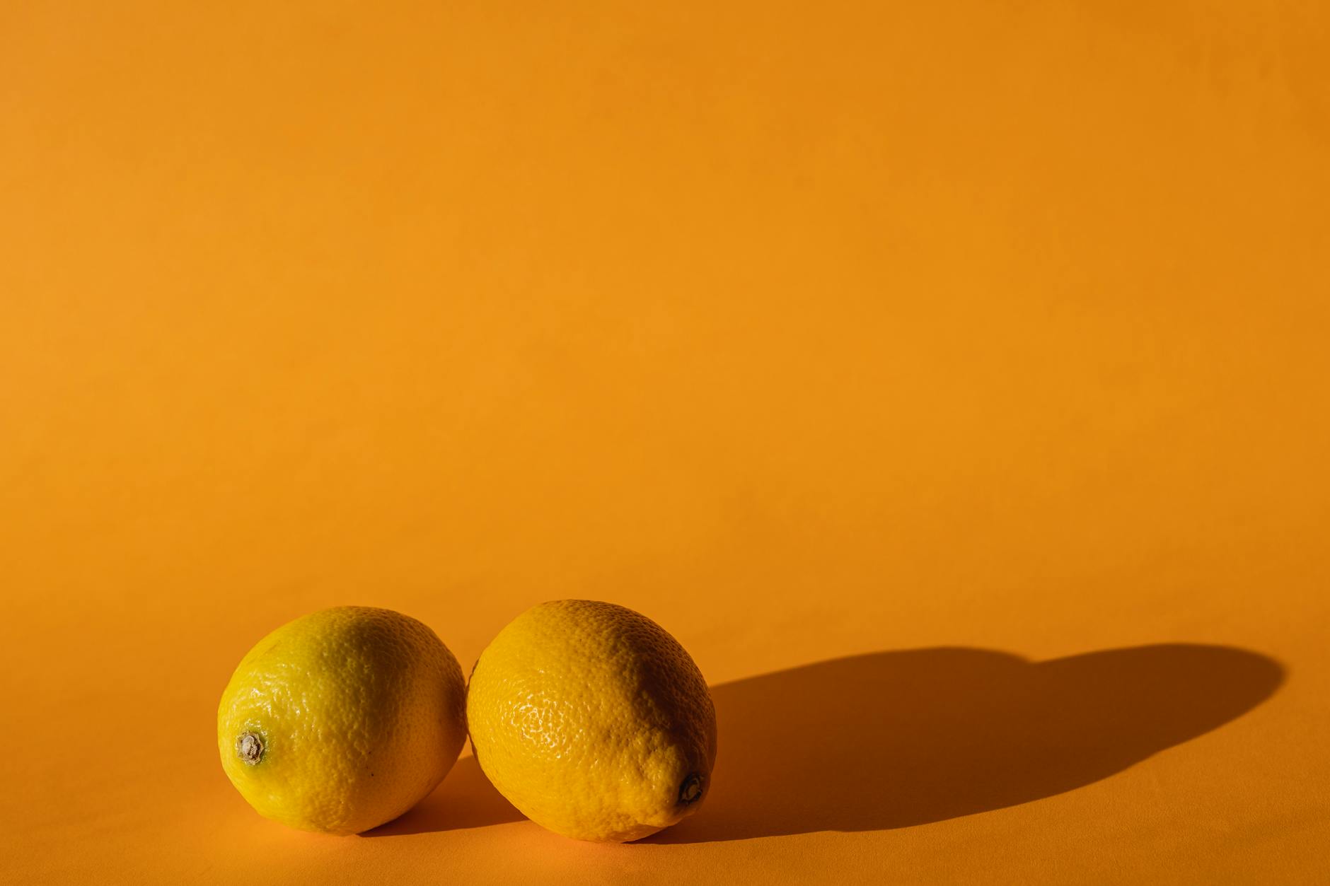 Gros plan d'une main tenant un vibromasseur orange contre un fond violet minimaliste